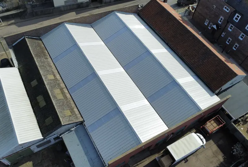 Aerial view of a completed commercial re-roof in new grey metal sheeting with rooflights