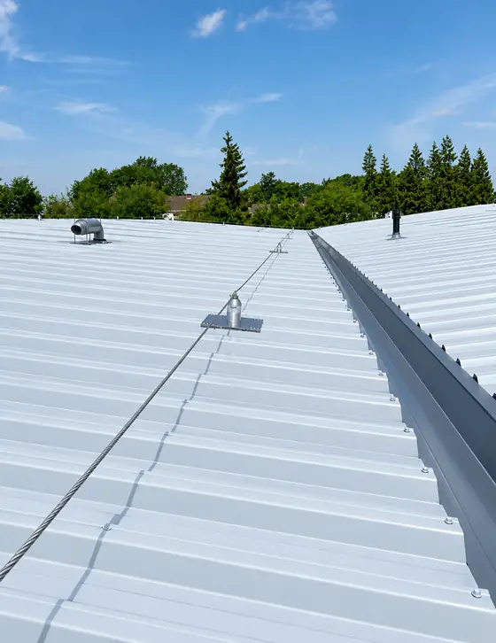 Rooftop safety line running across a white metal roof with intermediate anchor bracket
